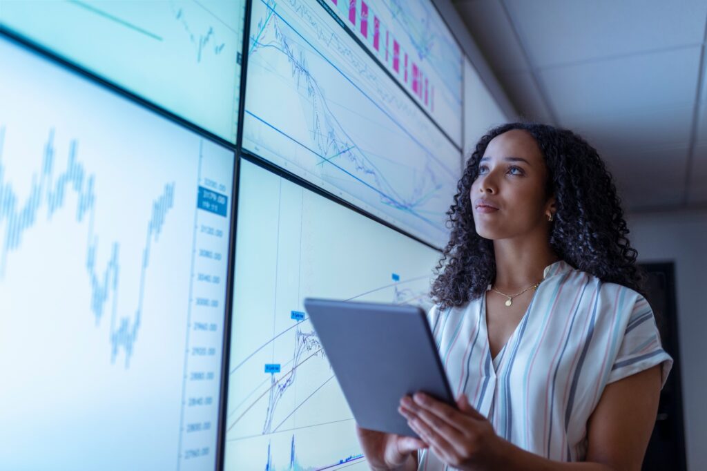 UK, York, Businesswoman with tablet looking at charts on interactive screens UK, York, Businesswoman with tablet looking at charts on interactive screens